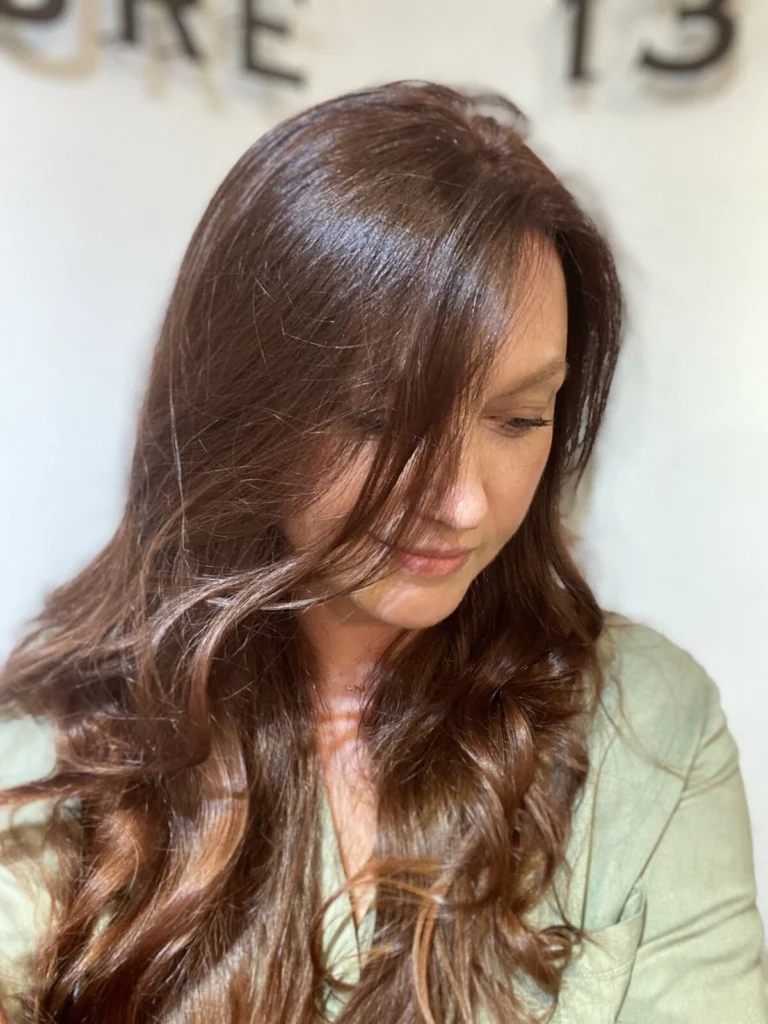 Brunette waves with soft caramel ends, at the salon window